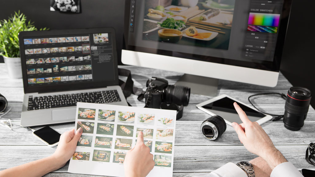 Personne sélectionnant des photos anciennes numérisées sur écran d'ordinateur avant impression